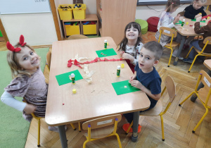 Dzieci przy stoliku ozdabiają pierniki