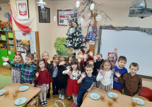 Dzieci odświętnie ubrane pozują do zdjęcia na tle świątecznej dekoracji