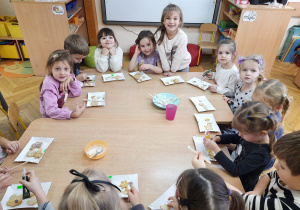 Dzieci przy stoliku ozdabiają pierniki