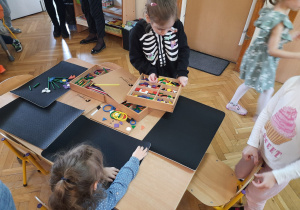 Dzieci przy stoliku na matach układają kolorowe drewniane klocki