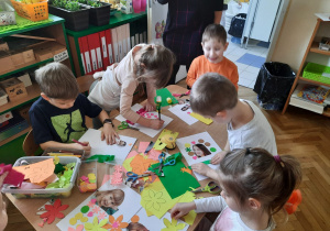 Dzieci przy stoliku z kolorowych kartek robią panią wiosnę