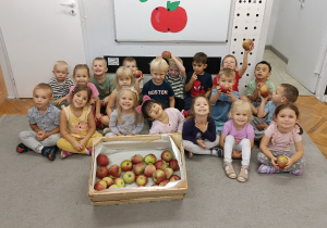dzieci siedzą przed tablicą z napisem dzień jabłka