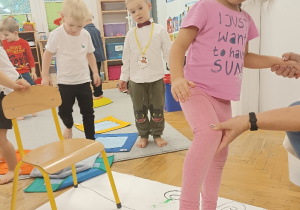 dzieci malują bosymi stopami na dużym arkuszu papieru