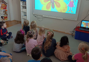 dzieci oglądają bajkę o motylach na tablicy multimedialnej