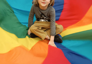 chłopiec siedzi na środku kolorowej chusty