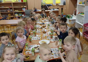 dzieci siedzą przy wspólnym długim stole zastawionym słodyczami