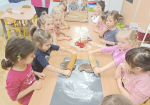 dzieci przy stolikach wałkują ciasto i wykrawają z niego pierniczki