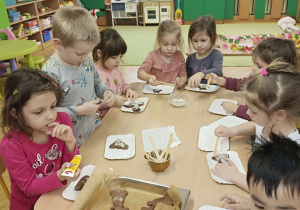 dzieci przy stolikach ozdabiają upieczone pierniki