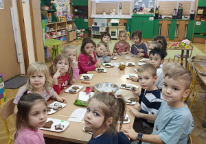 dzieci przy stolikach ozdabiają upieczone pierniki