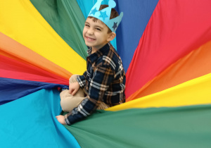 chłopiec w koronie siedzi na kolorowej chuście