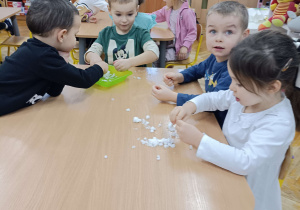 dzieci siedzą przy stoliku badają właściwości śniegu