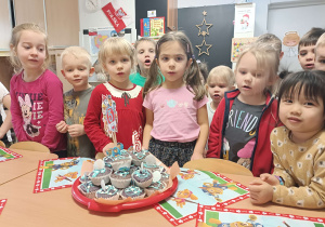 dzieci stoją dookoła tortu z babeczek