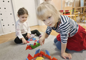 dzieci budują domki z klocków na dywanie