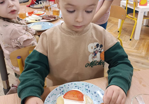 dzieci przy stoliku maja przed sobą na talerzykach kanapki z dużą ilością warzyw