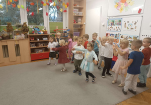 dzieci odświętnie ubrane tańczą na dywanie