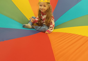 dziewczynka w koronie siedzi na kolorowej chuście