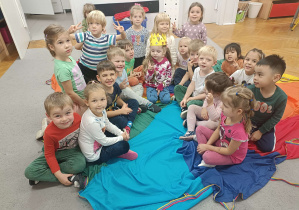 dzieci siedzą na kolorowej chuście