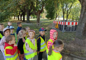 dzieci ubrane w kamizelki odblaskowe idą parami po chodniku