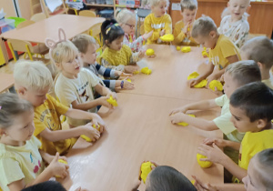 dzieci ubrane na żółto lepią z żółtej masy solnej