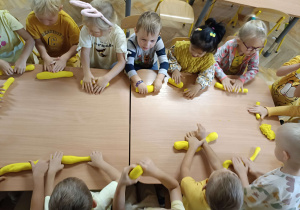 dzieci ubrane na żółto lepią z żółtej masy solnej