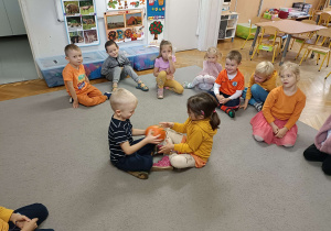 dzieci w kole podają sobie dynię
