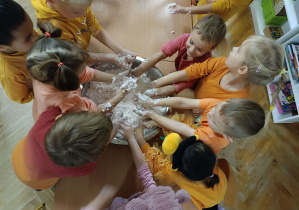 dzieci bawią się piaskoliną w kolorze pomarańczowym