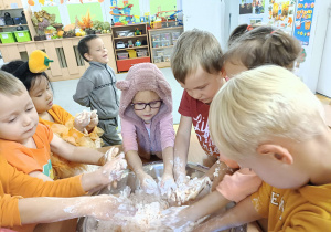 dzieci bawią się piaskoliną w kolorze pomarańczowym