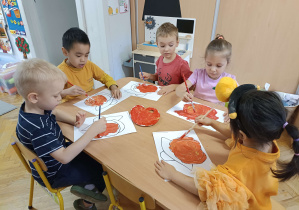 dzieci przy stoliku malują dynię