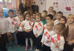 dzieci ubrane na galowo stoją na baczność w półkolu