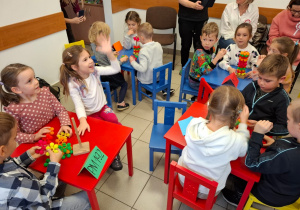 ci siedzą przy kolorowych stolikach