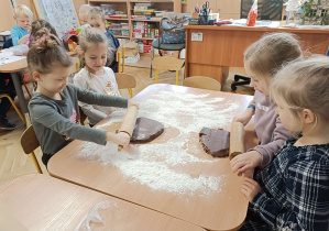 dzieci wałkują ciasto na pierniki na stoliku