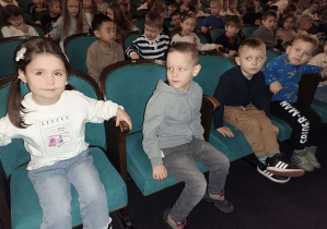 dzieci siedzą na fotelach widowni w teatrze