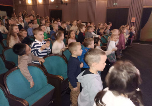 dzieci siedzą na fotelach widowni w teatrze