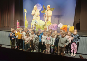 dzieci siedzą na fotelach widowni w teatrze