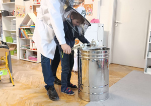 dziecko w kapeluszu ochronnym obsługuje wirówkę do miodu
