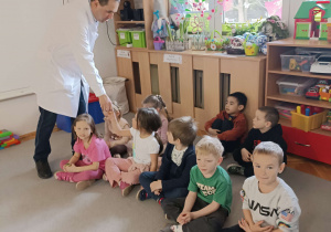 pszczelarz rozdaje dzieciom mini słoiczki z miodem