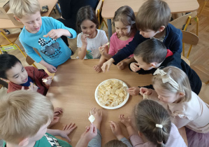 dzieci przy stoliku próbują miodu na wafelkach