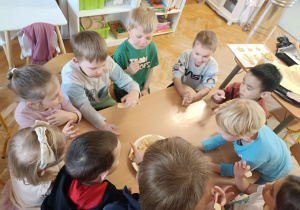 dzieci przy stoliku próbują miodu na wafelkach