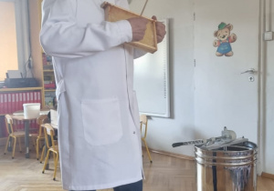 pszczelarz prezentuje dzieciom plaster miodu