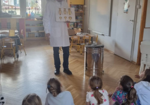 pszczelarz pokazuje dzieciom zdjęcia pszczół