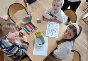dzieci przy stoliku wypełniają matematyczne karty pracy