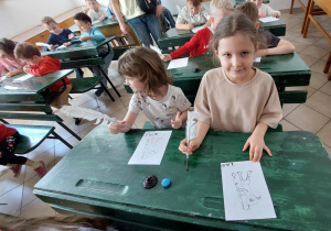 dzieci siedzą w starodawnych ławkach szkolnych