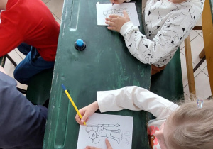 dzieci siedzą w starodawnych ławkach szkolnych