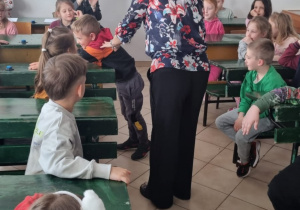 dzieci siedzą w starodawnych ławkach szkolnych