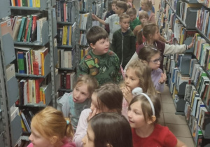 dzieci pomiędzy regałami z książkami