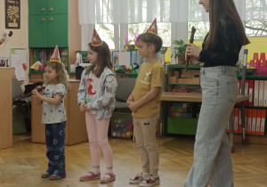 pani z trojgiem dzieci w czapeczkach urodzinowych gra na flecie