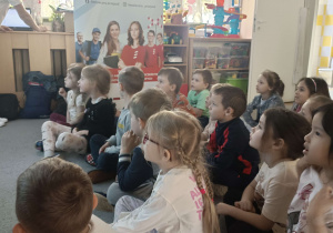 dzieci siedzą przed tablicą multimedialną