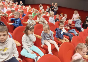 dzieci siedzą na fotelach teatru