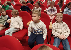 dzieci siedzą na fotelach teatru