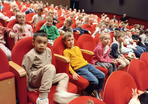 dzieci siedzą na fotelach teatru
